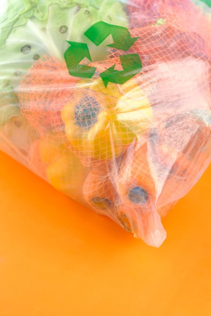 Um saco transparente com o símbolo verde da reciclagem com muitas frutas dentro mostrando como o plástico afeta a sua saúde