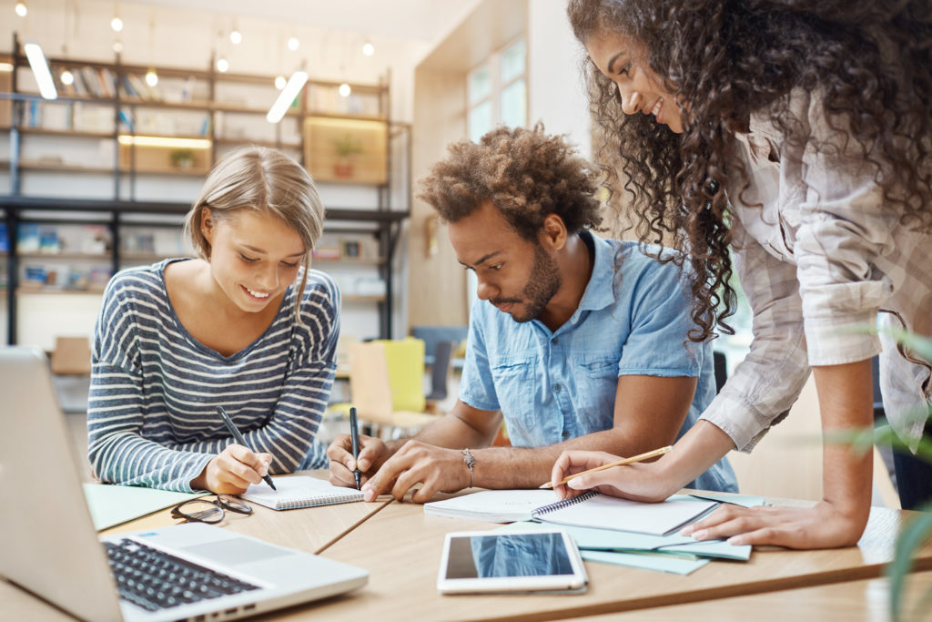 close-up-de-um-grupo-de-jovens-astronautas-sentado-na-biblioteca-fazendo-pesquisas-sobre-o-projeto-futuro-tem-olhando-atraves-de-graficos-no-laptop-escrevendo-novas-ideias