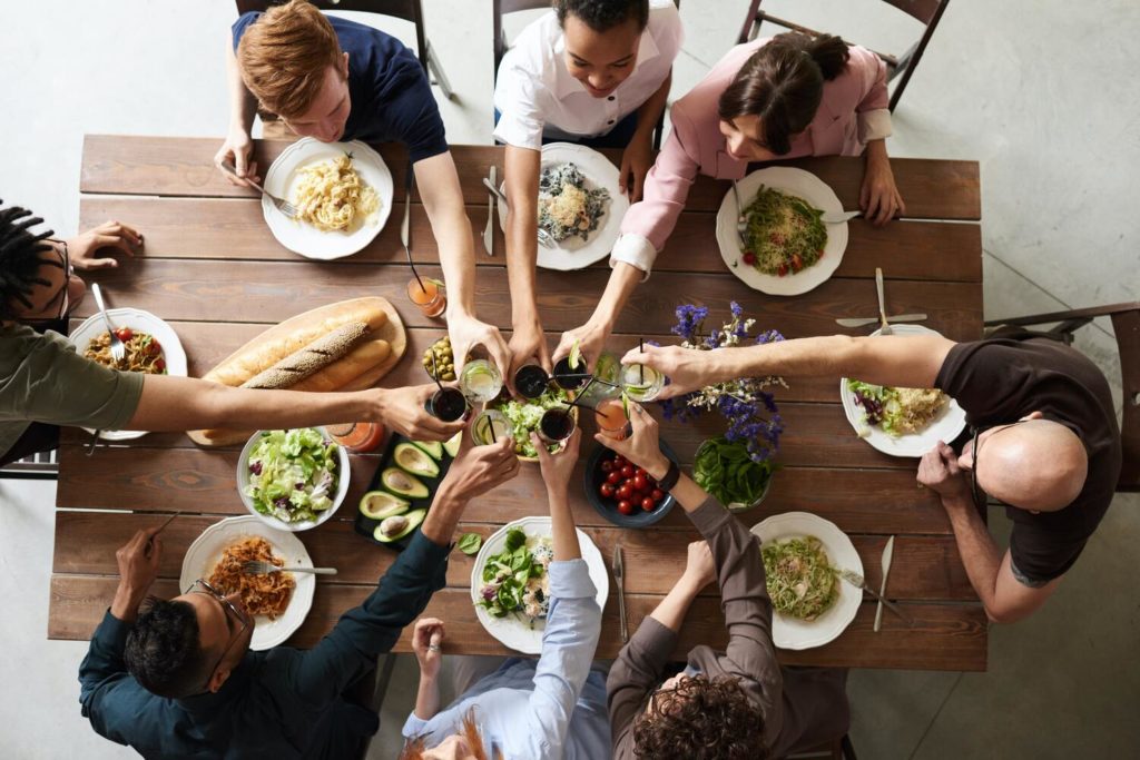 visão de cima de uma família sentada à mesa cheia de comida saudável, juntando as mãos, tipos de saúde