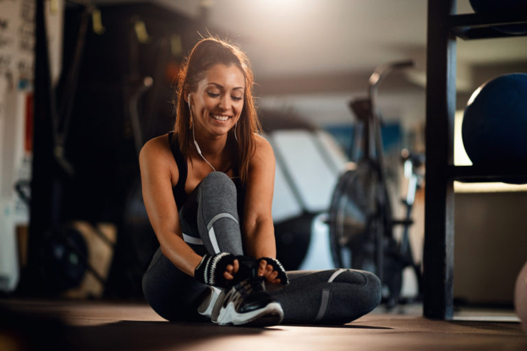 jovem desportista feliz se preparando para um treino e amarrando cadarco no centro de fitness