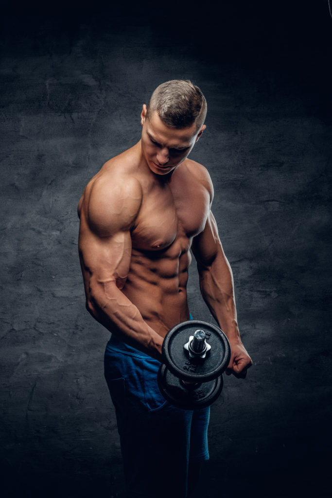 modelo de fitness masculino jovem sem camisa atletico detem o haltere com luz isolada em fundo escuro