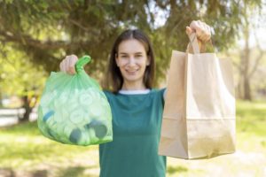 mulher segurando sacos de papel e plastico, consumo sustentável